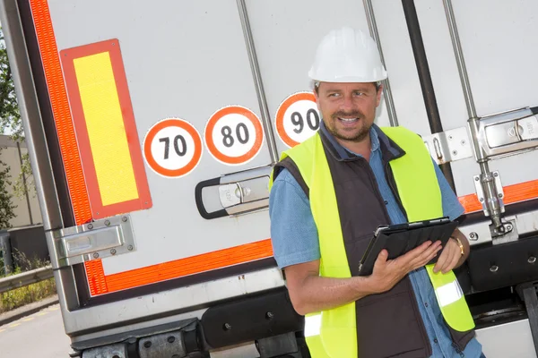 Portrait of delivery man smiling using digital tablet by truck