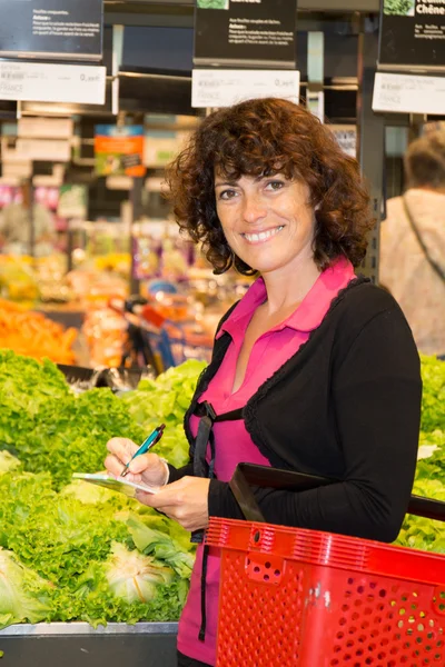Woman picking up, choosing green leafy vegetables in grocery store