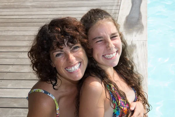 Smiling beautiful woman and young girl in pool