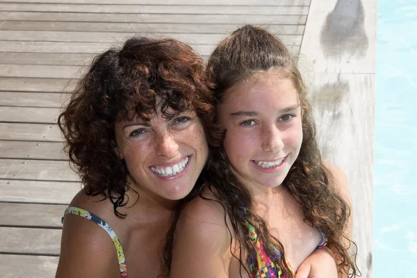 Smiling beautiful woman and young girl in pool