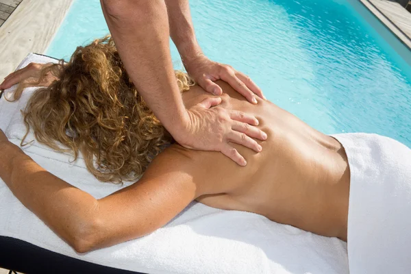 Woman receiving a back massage from a man at spa