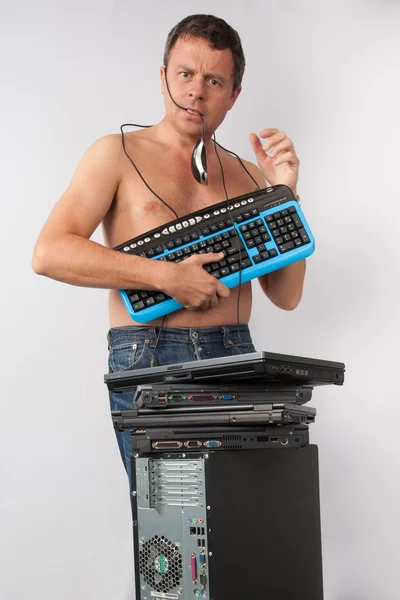 A man standing naked , hiding his body by computer keyboard