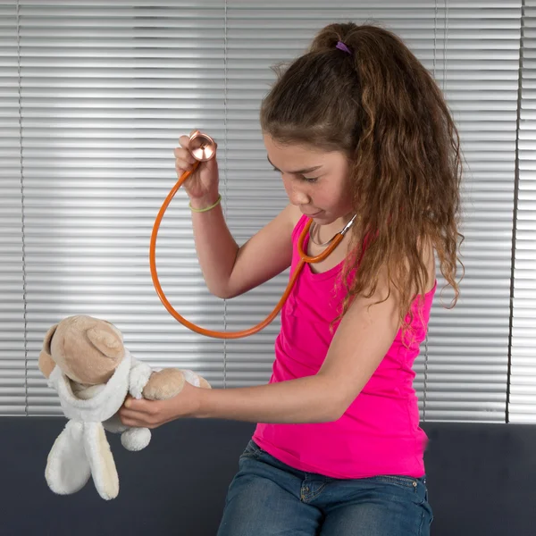 Beautiful girl listens by means of stethoscope as heart of toy bear