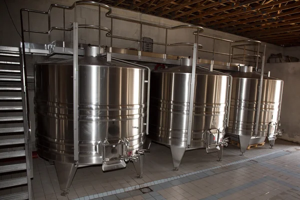 Stainless steel wine vats in a row inside the winery