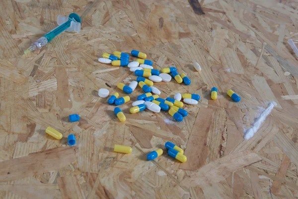 Pills, syringe and cooked heroin on wooden table