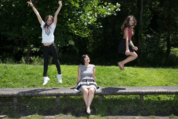 Family, mother and her two daughter jumping at the park