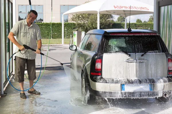 Man washing his car with a high pressure water jet