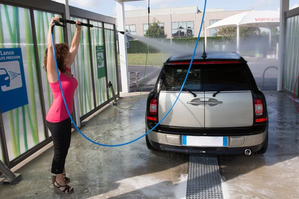 Woman washing his car with a high pressure water jet