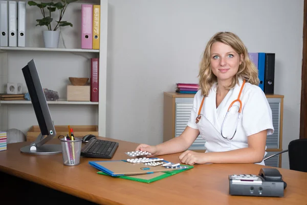 Attractive blonde doctor with pills on her desk