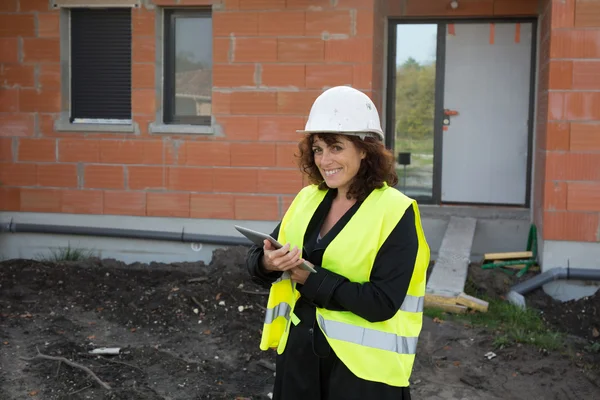 Mature female architect or construction engineer on building site supervising