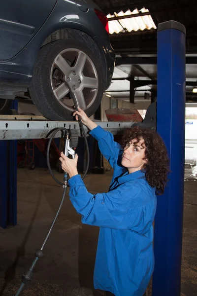 Woman as female car mechanic working on an auto in workstation