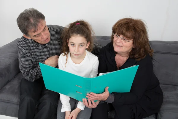 Grand Father  and grand mother helping grand daughter to do their homework in their living room