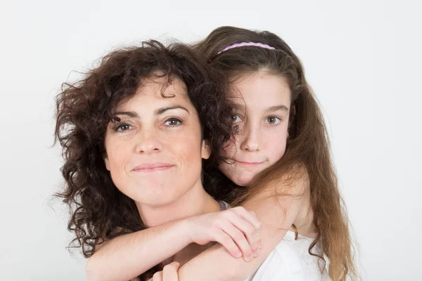 Mother giving her daughter a piggyback ride against white background