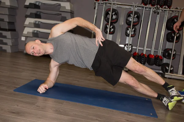 Happy man doing  exercises on gym mat in fitness center