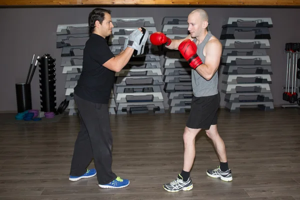Two boxing men exercising together at the health club