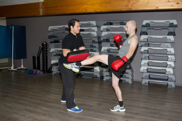 Two boxing men exercising together at the health club