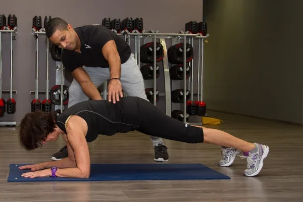 Middle aged Woman doing sport exercises with coach at fitness center