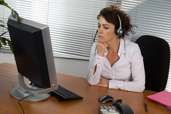 Woman telephonist in the white blouse at desk