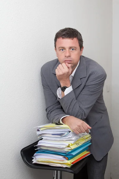 Man with stack of work and folders, fed up