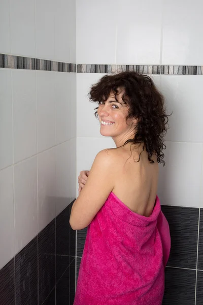 Back view of a woman body entering in the shower with a pink towel