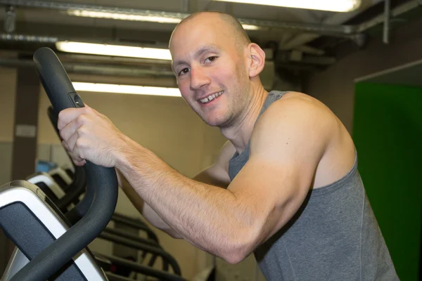 Cycling fit man on bike in gym smiling