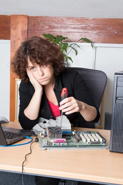 Bored woman fixing a computer at work