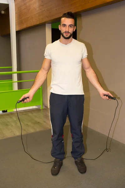 Young man exercising with jump-rope at the gym