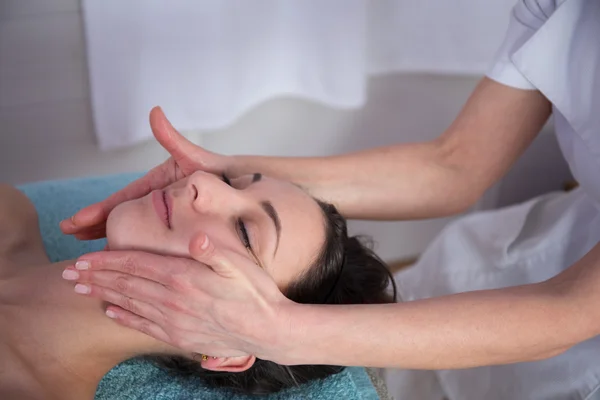 Attractive young woman is getting head massage at spa.