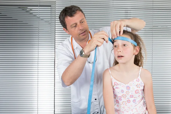 Doctor measures growthgirl in medical office, focus on girl