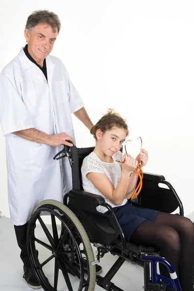 Smiling little girl sitting on the wheelchair looking at the doctor in the hospital