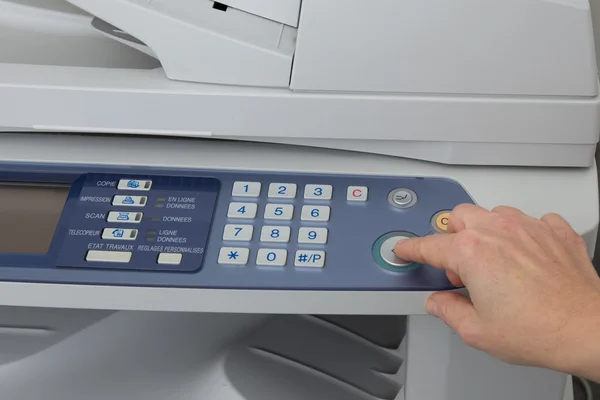 Woman holding finger on start button of laser printer