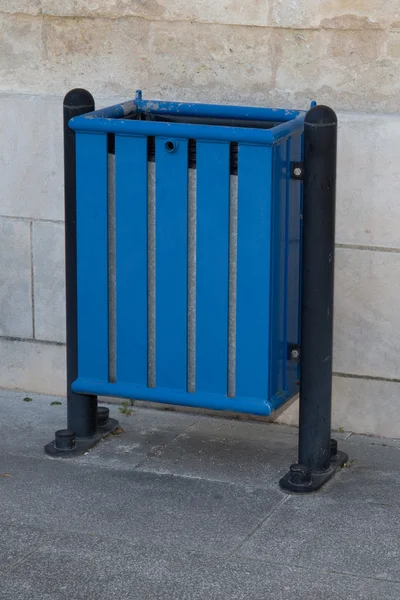 Blue bin in the street , stone wall isolated