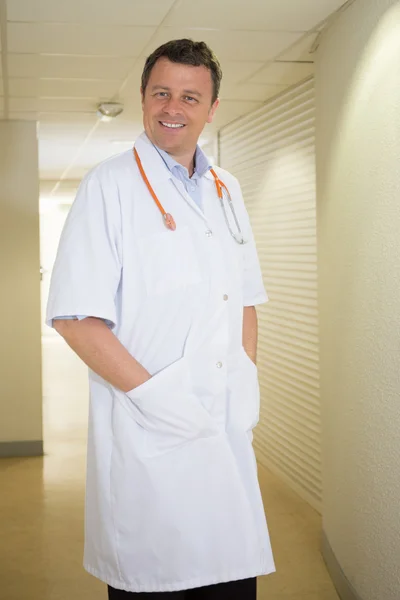 Smiling doctor with stethoscope in hospital hall