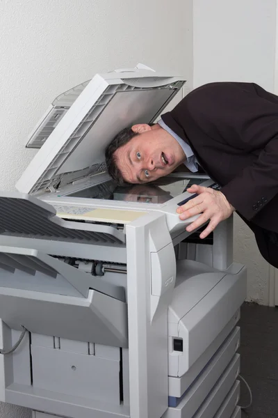 Side view of a man putting his head in copy machine