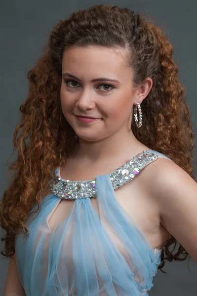 Teen beauty head shot in light blue dress to left.