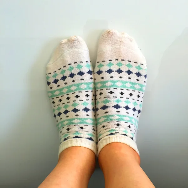 Selfie feet wearing white polka dot socks on white floor background