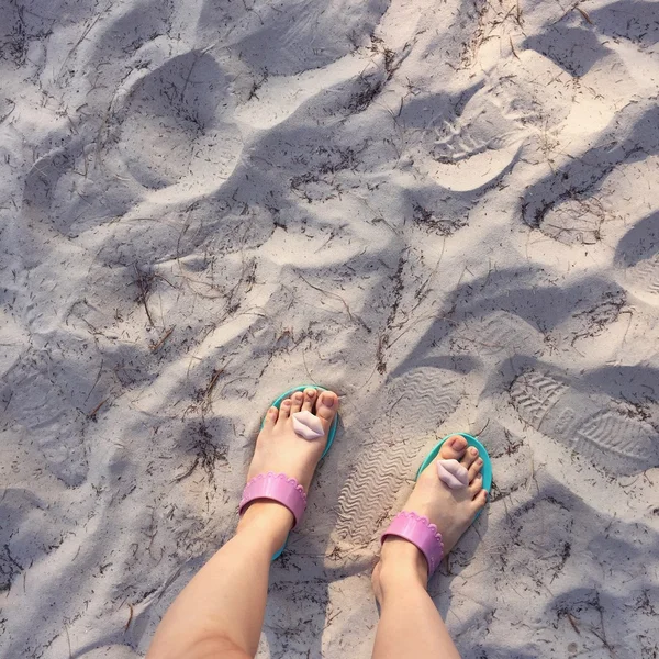 Selfie of woman feet wearing flip flops on a beach,