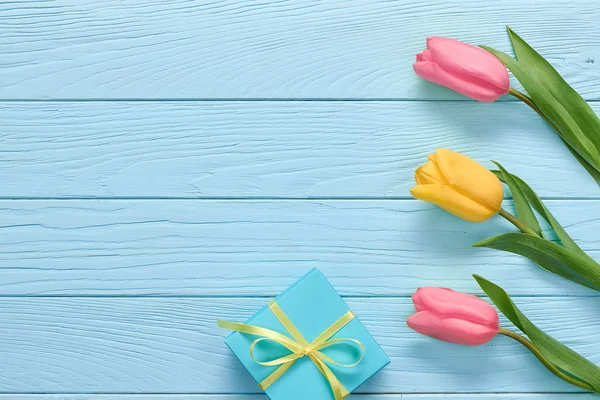 Mothers Day background. Tulips, gift box on wood