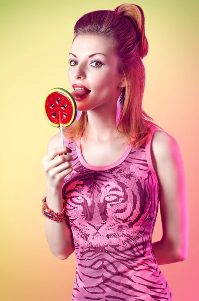 Portrait of mischievous redhead girl licking big lollipop. Fashion dressed