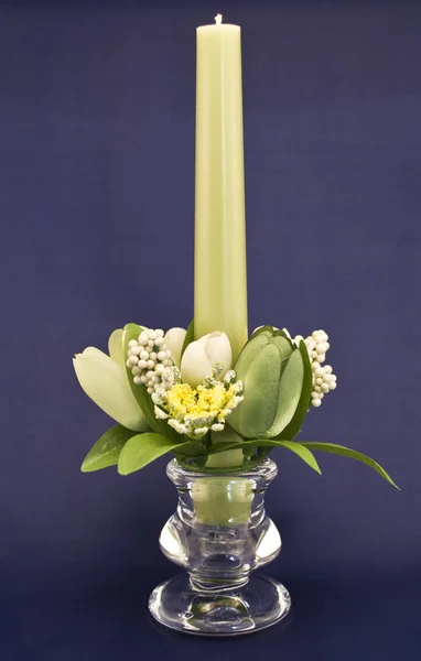 Candle holder with green pillar candle against blue background