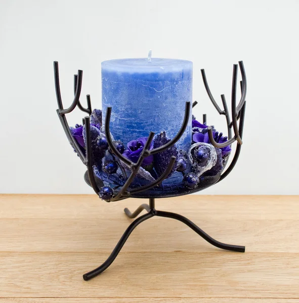Candle holder with blue pillar candle against white background