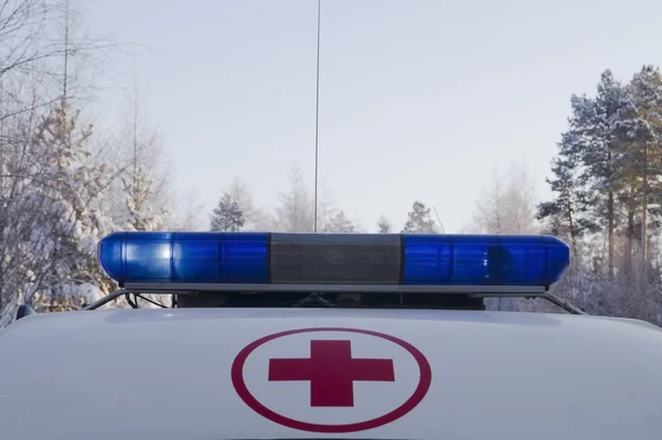 Red cross in the red circle and working blue flashing beacons on the roof of the ambulance