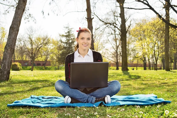 Student in a park looking something on her laptop