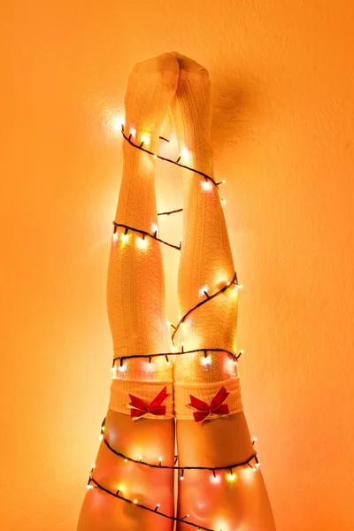 Female legs wrapped with christmas tree lights