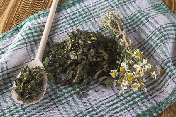 Spoon of dried herbal tea leaves and chamomile flowers.