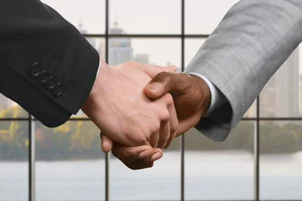 Businesspeople shake hands at daytime.