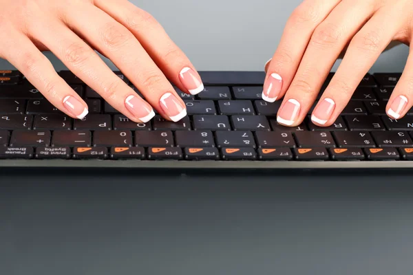 Womans fingers on wireless keyboard.