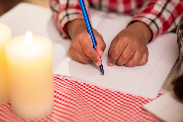Child writes letter by candlelight.