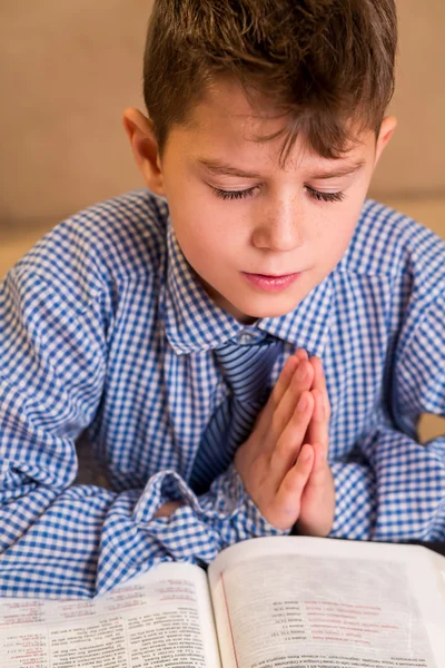 Boy praying with eyes closed.