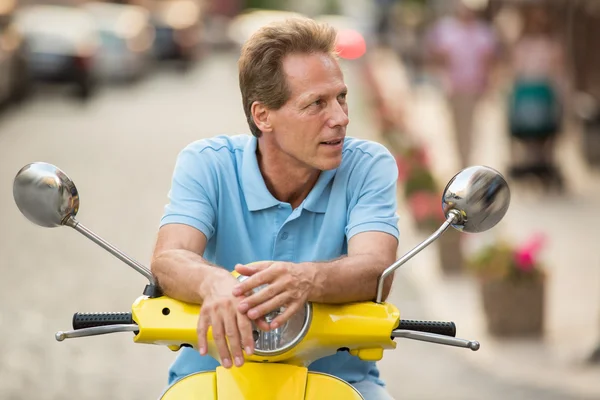 Mature man sitting on scooter.